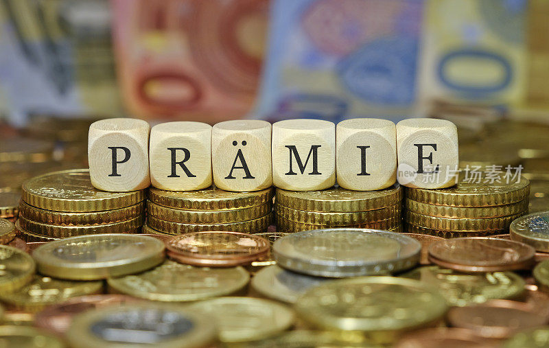 Bonus / Finance and business concept.	The word "PRÄMIE" in german language, on a stack of euro coins and banknotes.